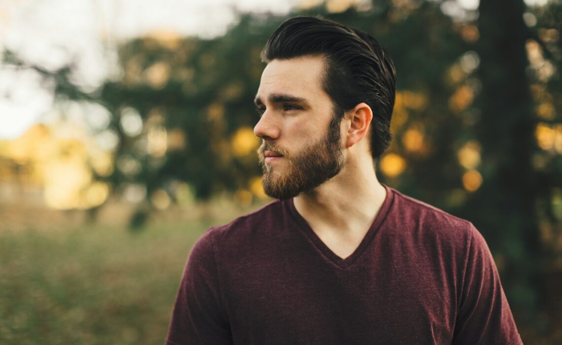 man wearing maroon V-neck t-shirt in forest