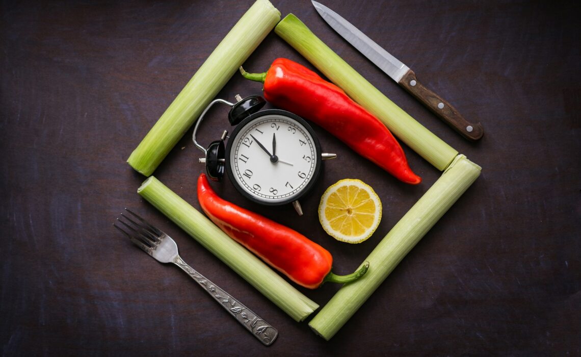 a clock surrounded by vegetables and a knife